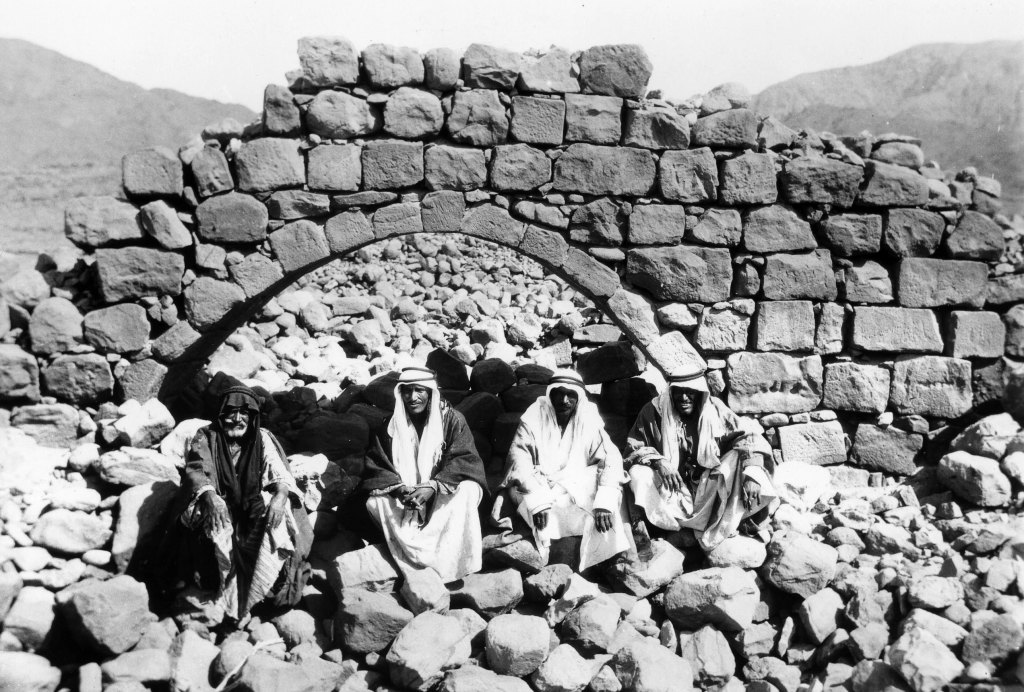 Four local men sit by the ruins of an aqueduct